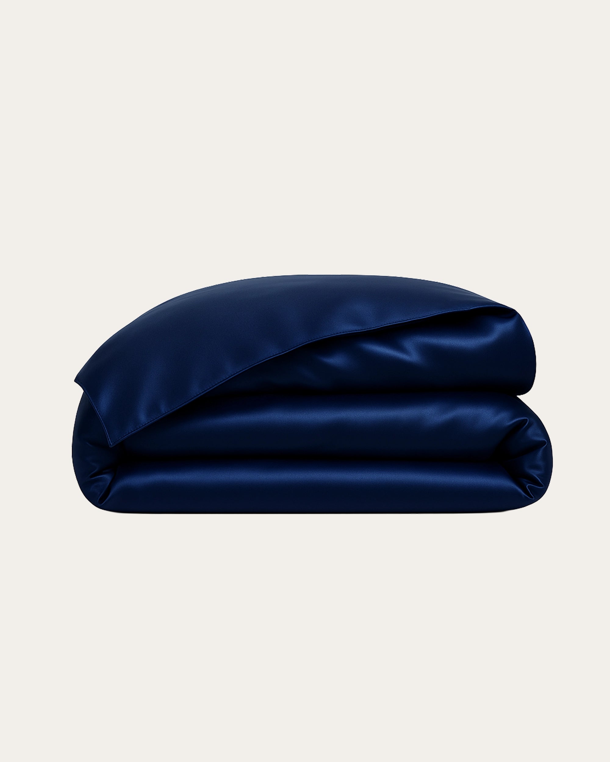 Midnight blue satin duvet cover stacked elegantly, showcasing its smooth and luxurious texture.