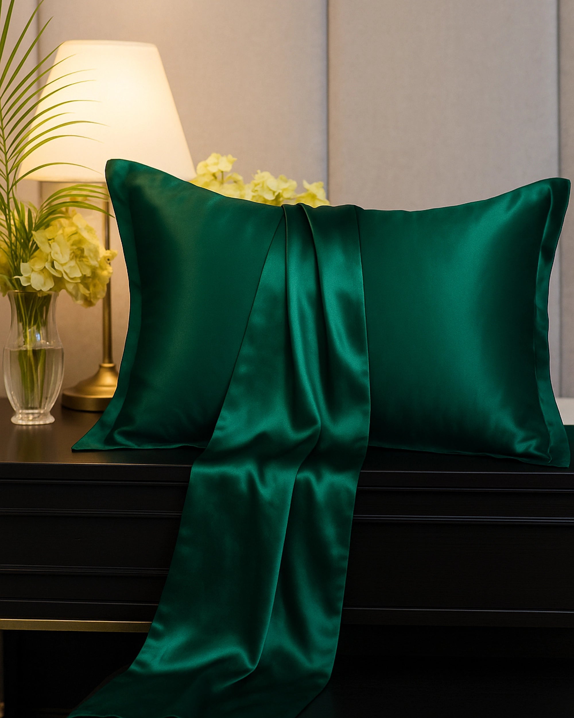 Pine green satin Oxford pillowcase draped elegantly on a nightstand, showcasing its luxurious sheen and vibrant hue.